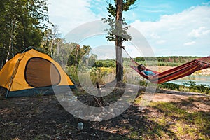 woman laying on hammock at camp near lake summer hiking concept