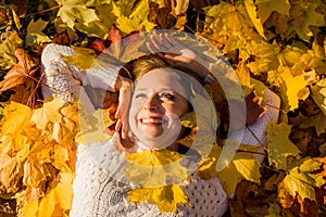 Woman laying in maple leaves in the park.