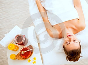 Woman laying on massage table near honey spa therapy ingre