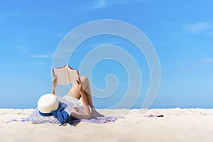 Woman laying and reading on the beach with blue sky in summer times. photo