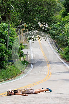 A woman is laying on the road, and the road is empty