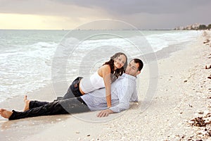 Woman laying on top of man at beach looking at vie