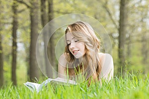 Woman lays on grass and reads book