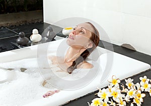 Woman lays in soapsuds in bathing