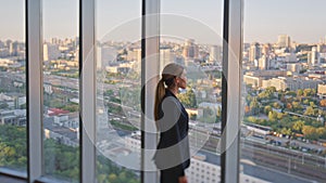 Woman leader thinking future looking panoramic window in contemporary office.