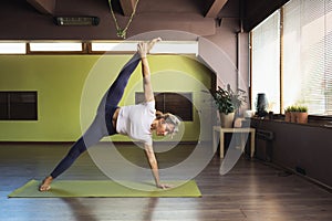 A woman leading a healthy lifestyle, doing yoga, performs in the studio the exercise vasishthasana, the pose of the sage