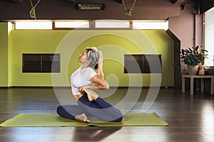 A woman leading a healthy lifestyle, doing yoga, sitting on a mat, performs the exercise eka pada rajakapotasana