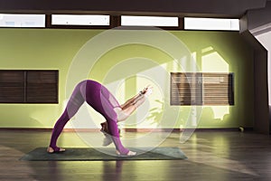 A woman leading a healthy lifestyle and practicing yoga, performs the exercise prasarita padottanasana, bend forward with a step