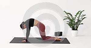 A woman leading a healthy lifestyle and practicing yoga, performs the Marjariasana exercise, cat pose