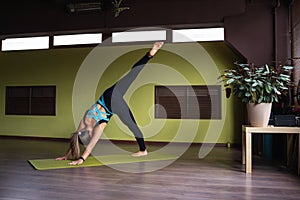 Woman leading a healthy lifestyle and practicing yoga, performs a variation of the exercise Adho Mukha Svanasana