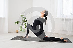 A woman leading a healthy lifestyle and practicing yoga, performs a variation of the Virabhadrasana exercise