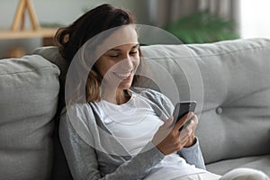 Woman leaned on sofa enjoy lazy weekend with smartphone