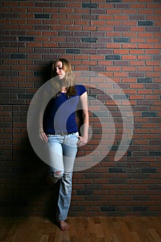 Woman leaning against brick wall