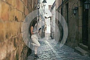 woman leaning against a stone wall using a cell phone