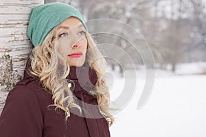 Woman leaning against tree in winter