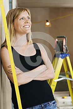 Woman Leaning Against Wall With Ladder Behind