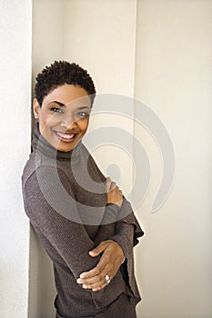 Woman leaning against wall smiling.