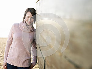 Woman Leaning Against Wooden Hull On Beach