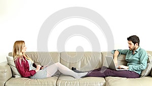 Woman leaning on couch speaking to sitting young man