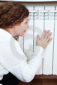 Woman leaning his hand and cheeks to radiator