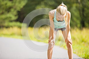 Woman leaning on knees and catch breath after stamina workout photo