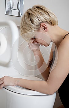 Woman leaning on open toilet seat at indoor bathroom