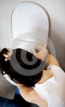 Woman leaning on open toilet seat at indoor bathroom