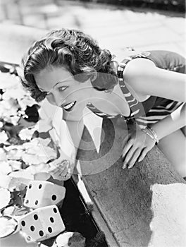 Woman leaning over a fountain with dice in the water