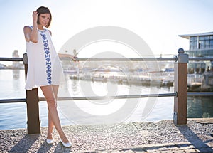 Woman leaning on railing next to water wearing summer dress