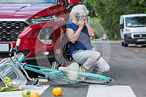 Woman leans against her red car and calls for help after causing an accident