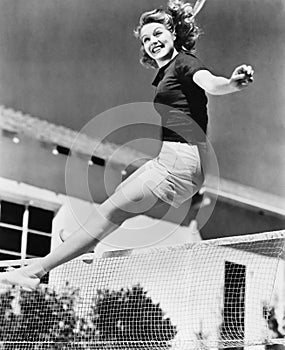 Woman leaping over a tennis net photo