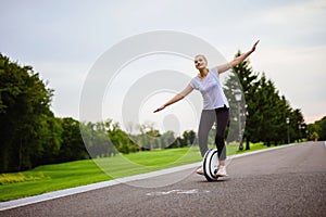 A woman learn how to ride a monocycle. She tries to keep her balance.