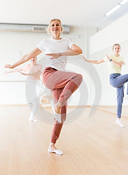 Woman learning aerobic dance during group training in studio