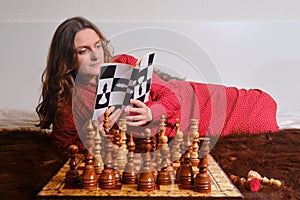 Woman learning chess from book  self study board game at home