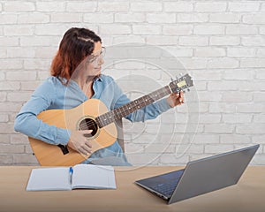 A woman is learning to play the guitar online. Remote music lesson