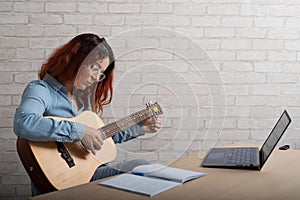 A woman is learning to play the guitar online. Remote music lesson