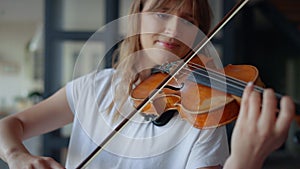 Woman learning to play violin at home. Romantic girl playing violin with bow