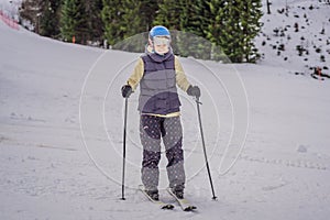 Woman learning to ski. Young woman skiing on a snowy road in the mountains