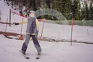 Woman learning to ski. Young woman skiing on a snowy road in the mountains