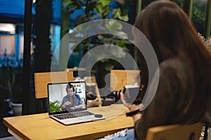 Woman is learning to use camera thru tutorial by laptop. Asian female watching online training workshops for camera function by