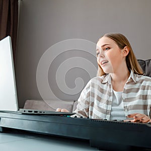 Woman learns music singing vocals playing piano online using laptop at home interior. Teenager girl sings song play