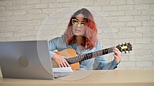 Woman learns to play guitar from video on laptop. Distance learning music in quarantine