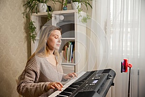 Woman learns to play the piano with a teacher online