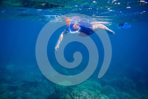 Woman learns to snorkel in full face mask. Underwater coral landscape and snorkel