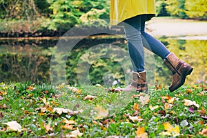 Woman in leather boots is walking in an autumn park