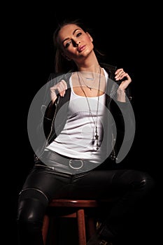 Woman in leather clothes is pulling her collar and sits