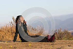 Woman in leather jacket seated on ground laughing