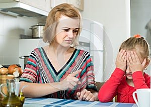 Woman lecturing small female child in the kitchen