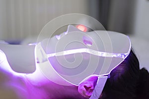 Woman With Led Light Therapy Facial Beauty Mask Photon Therapy. Woman receiving face light therapy in LED mask