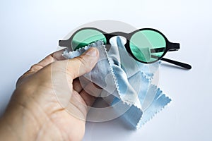 Woman left hand cleaning black sunglasses by microfibre cleaning cloths, On white background, Close up shot, Optical concept